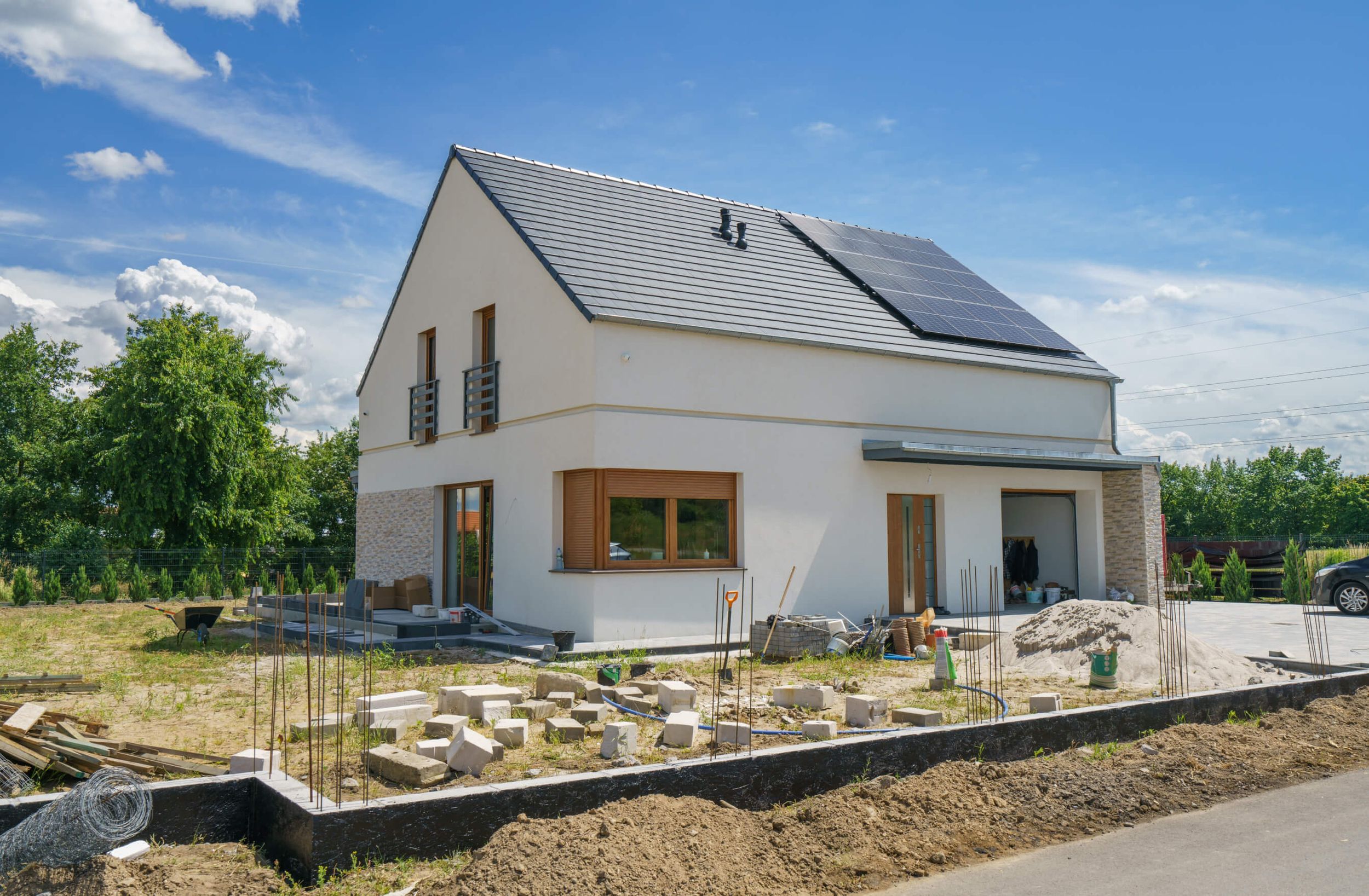 Ein weißes Einfamilienhaus, vor dem ein neuer Zaun gebaut wird