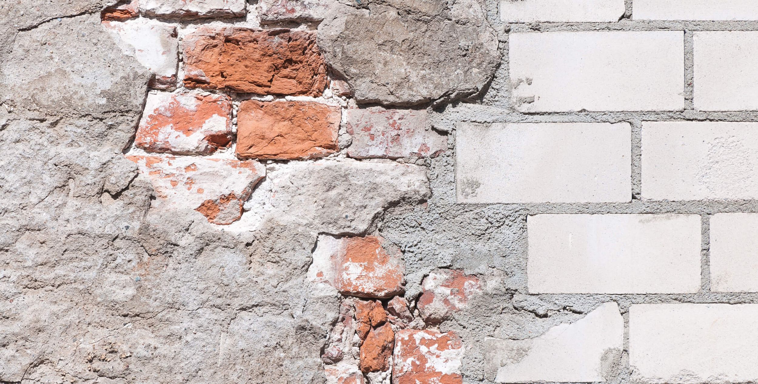 Eine Mauer aus Ziegelstein, die zum Teil kaputt und zum Teil ganz ist